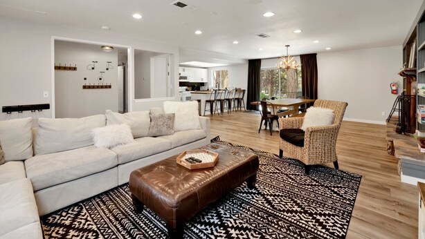A modern living room with a sofa, ottoman, and dining area.