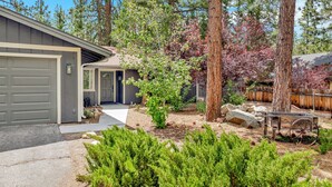 A residential property with a garage, a front yard with a small tree, and a wooden fence.