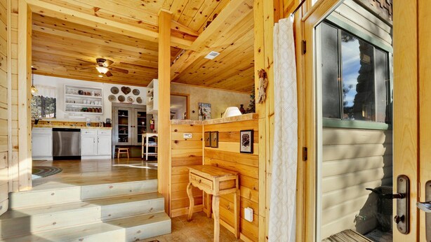 Interior de madera con cocina, comedor y una escalera que sube a un altillo.
