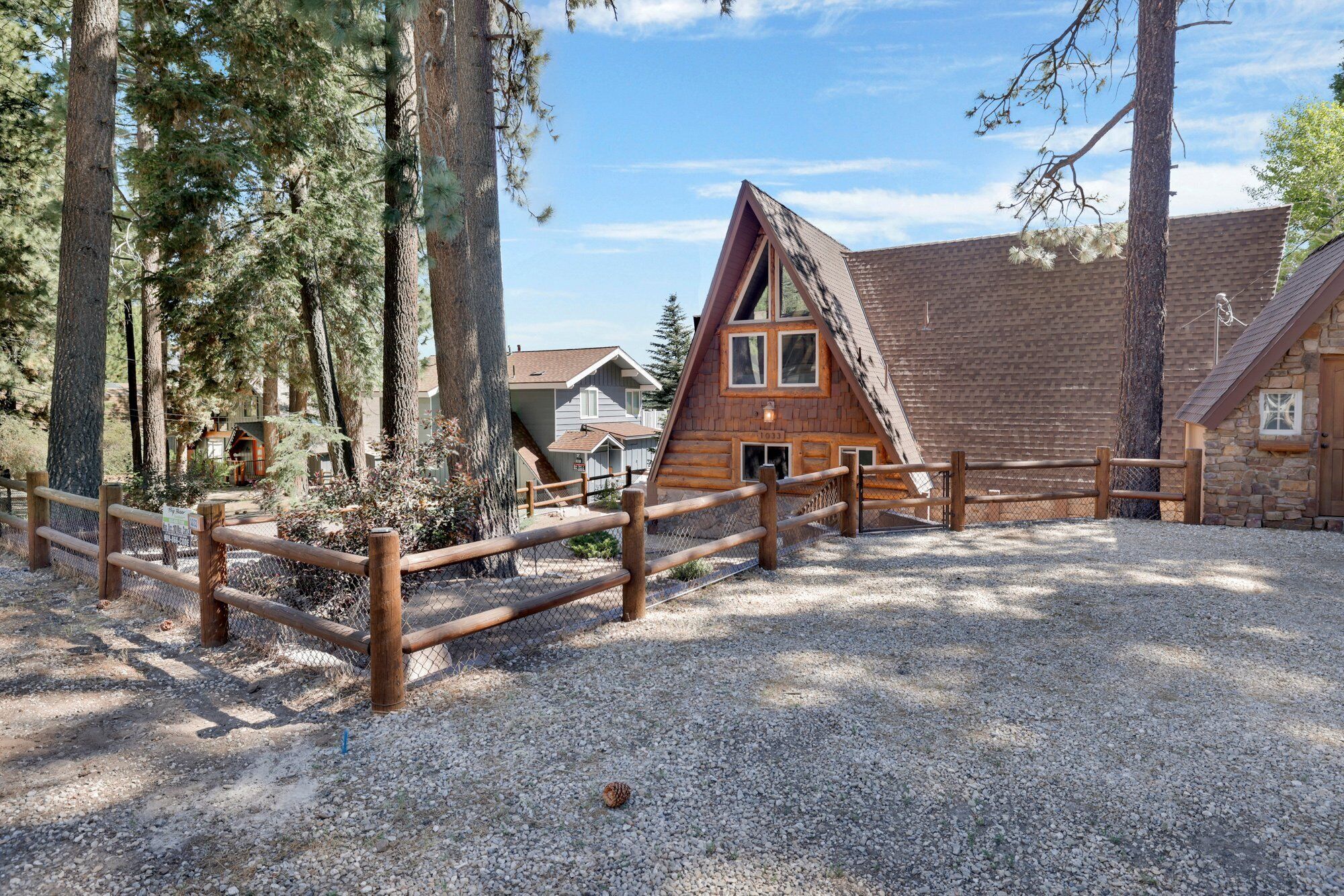 Une cabane dotée d’un toit en pente, entourée d’une clôture en bois et dont le sol est recouvert de gravier.