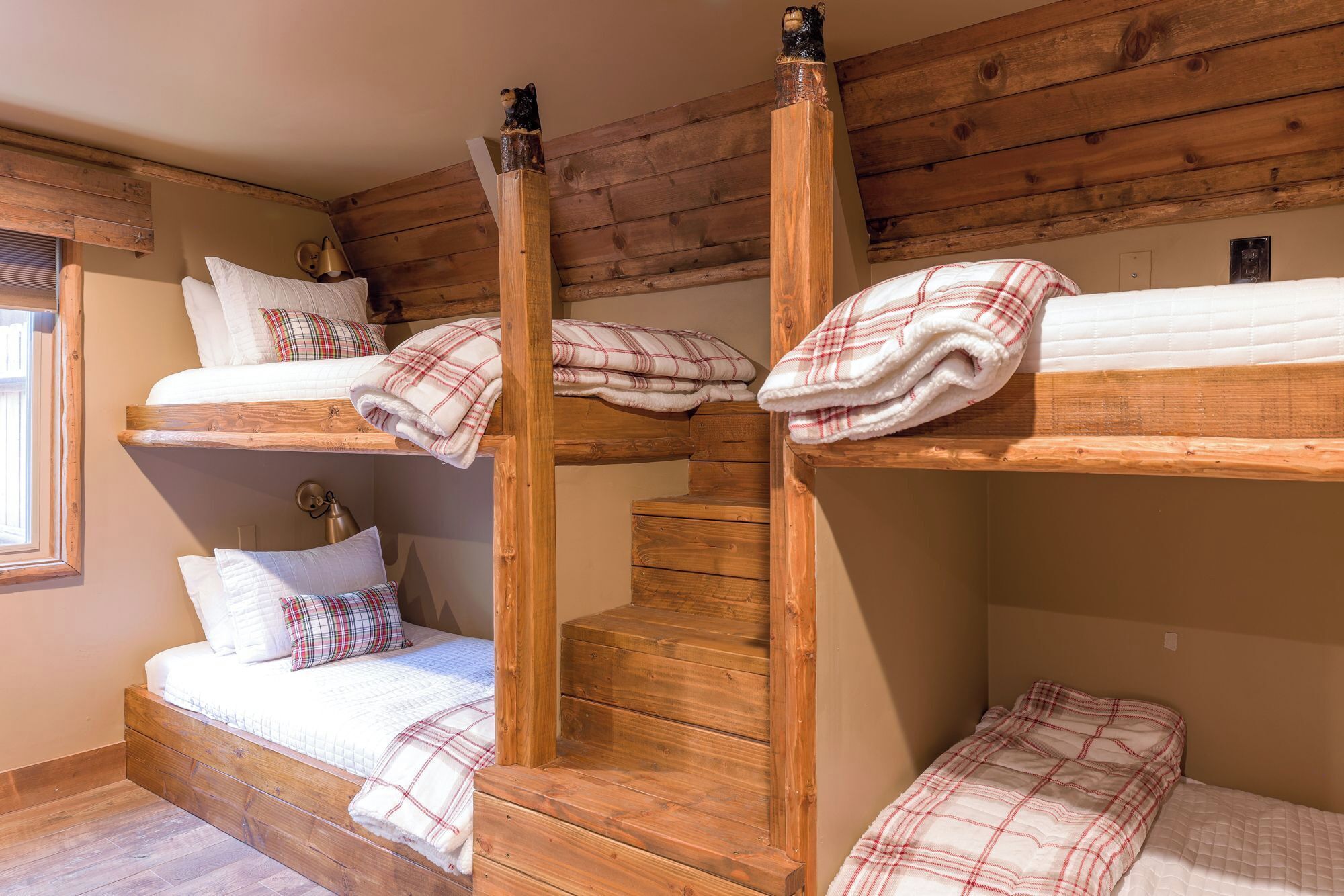 Een slaapkamer met stapelbedden, houten balken en een raam.