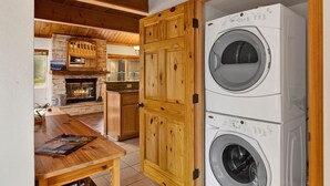 Ein Waschraum mit zwei übereinander gestapelten Waschmaschinen und einem Holzkasten.