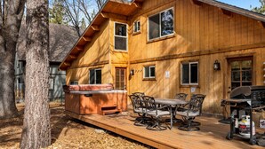 Eine Holzhütte mit Whirlpool, Sitzgelegenheiten im Freien und Grillplatz.
