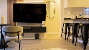 Een moderne keuken met een groot flatscreen televisietoestel, een bar met krukken en een eettafel.