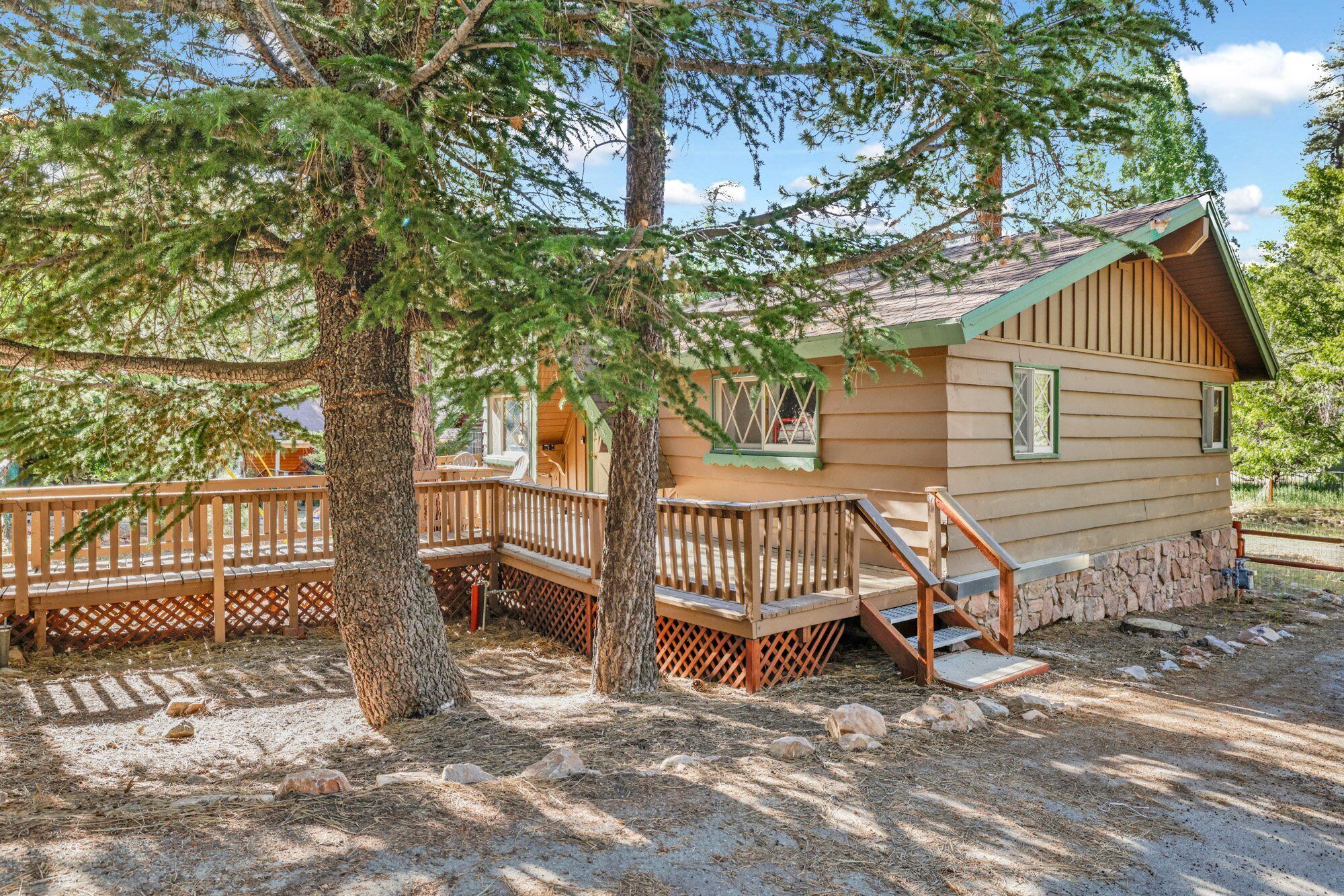 A cabin with a wooden deck, a staircase, and a view of the surrounding forest.