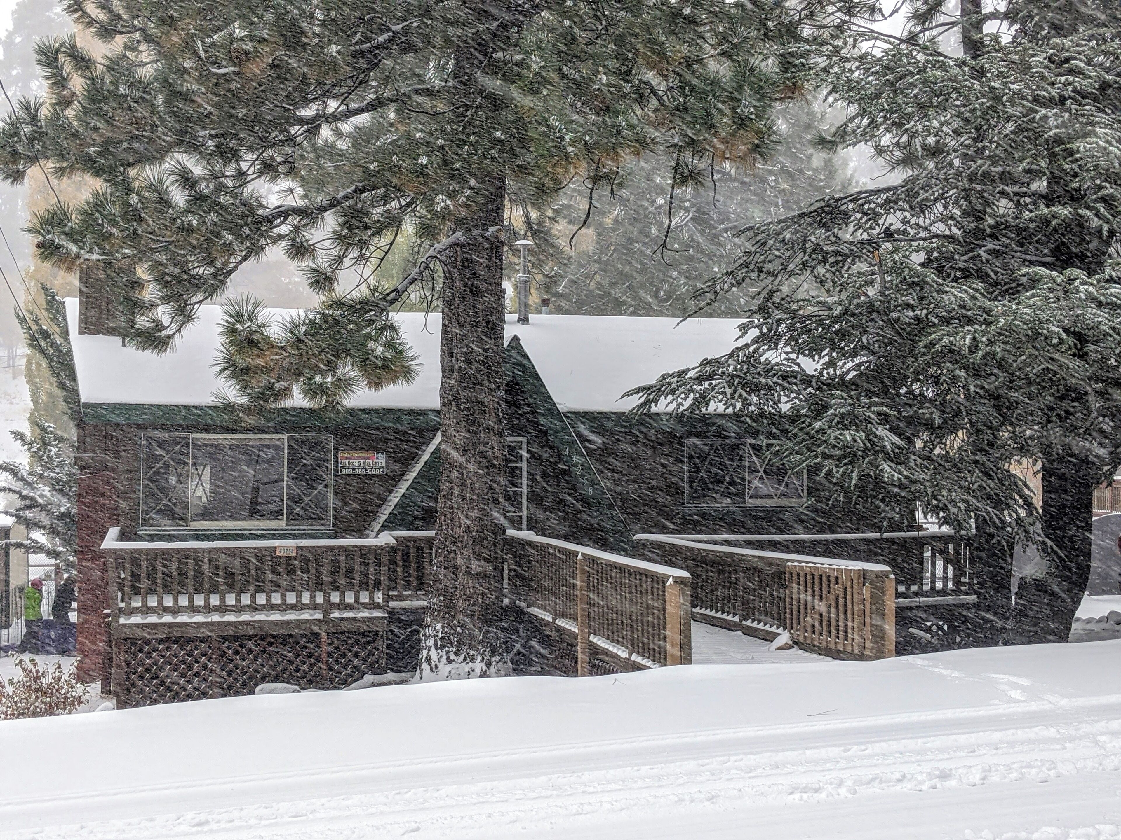 A snow-covered cabin with a wooden deck and a glass enclosure.