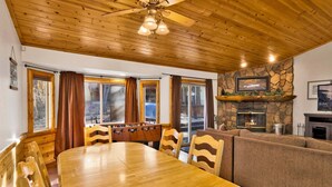 Comedor con suelo de madera, una mesa y sillas, chimenea de piedra y un sofá.
