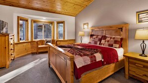 Un dormitorio de madera con cama, mesitas de noche, cómoda y ventana con vistas.