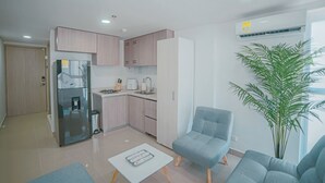 A modern kitchen with a refrigerator, sink, and countertop appliances. There is a seating area with a chair and a table. - Armonioso loft de 1 Hab en Ctg (Cartagena de Indias)