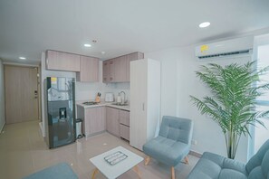 Eine moderne Küche mit Kühlschrank, Spüle und Einbaugeräten. Es gibt eine Sitzecke mit einem Stuhl und einem Tisch.