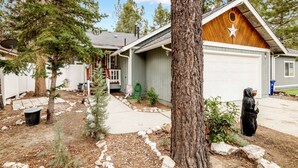 Una casa residenziale con garage, un portico anteriore e un piccolo giardino piantumato con alberi e un aiuola rocciosa.