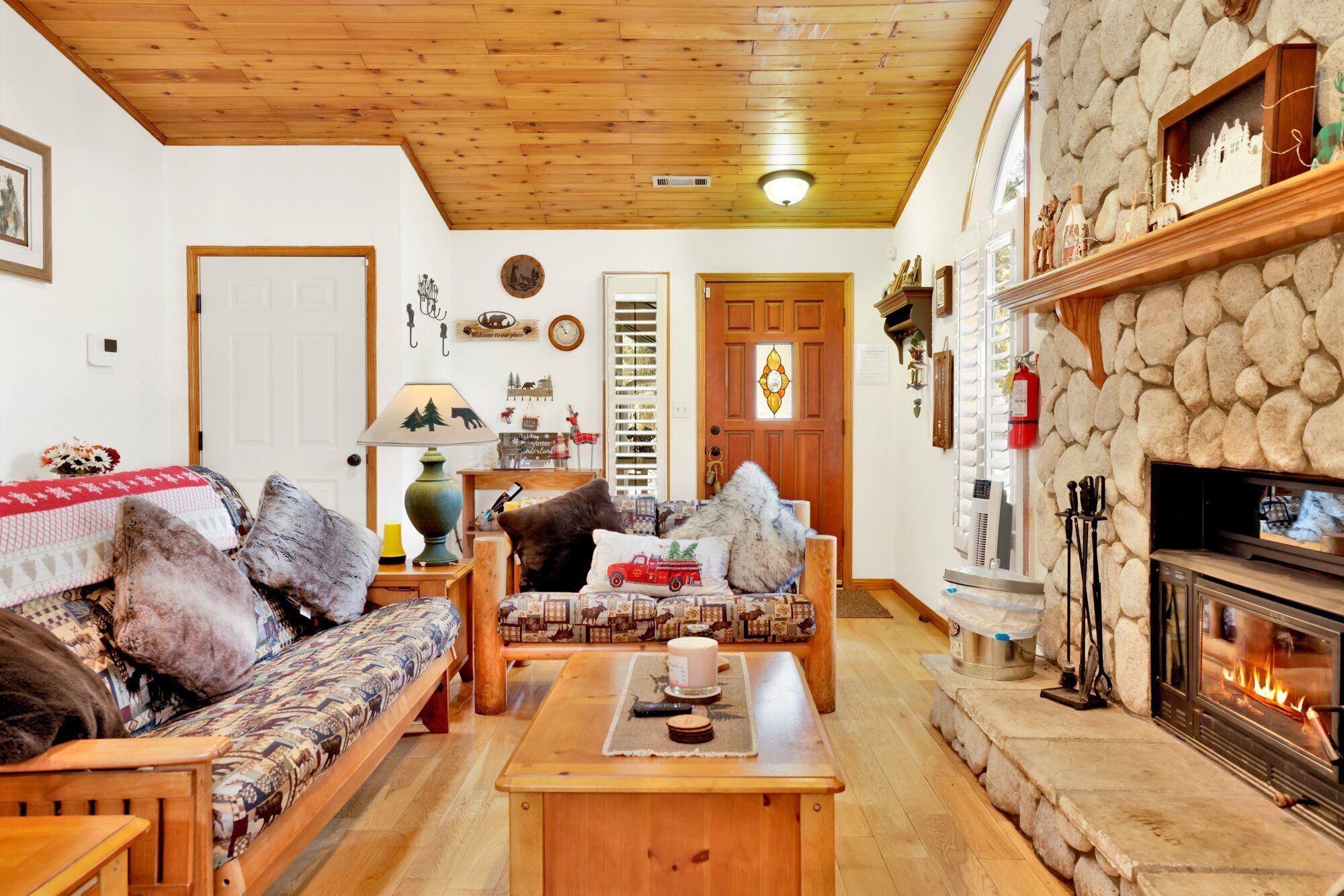 Ein gemütliches Wohnzimmer mit Kamin aus Stein, Holzmöbeln und Kaminbesteck.