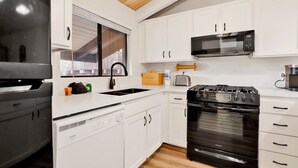 Een moderne keuken met witte kasten, een roestvrijstalen fornuis, een magnetron en een vaatwasser.