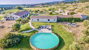 Une villa dotée d’une piscine, de bâtiments en pierre et entourée d’un paysage verdoyant.