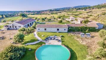 Eine Villa mit Swimmingpool, Steingebäude und umliegender Landschaft.