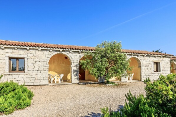 A stone building with arched doorways and a gravel courtyard.