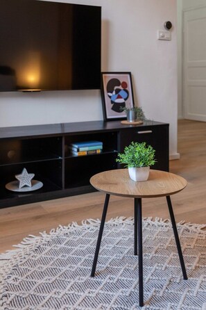 Relax in this stylish living room with a round coffee table, flat-screen TV, and cozy reading nook.