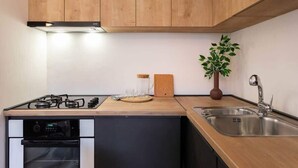 A kitchen with wooden cabinets, a gas stove, a dishwasher, a sink, and a potted plant.