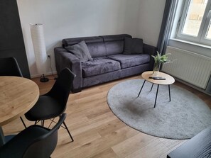 Cozy living space with a sofa, dining area, and large window offering a view.