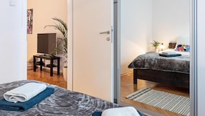 A modern bedroom with a bed, a desk, and a potted plant.