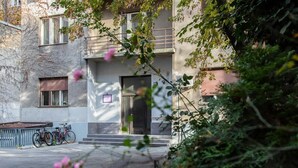 A building with a dark entrance door, a small balcony, and a bicycle parked outside.