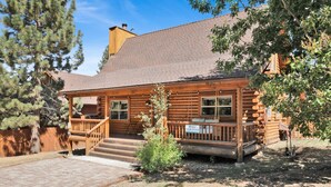A log cabin with a porch, a chimney, and a sign indicating parking availability. - Binky's Mountain Hideaway #2455 (Big Bear Lake)