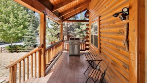 A wooden cabin with a covered porch, a grill, and a welcome sign. - Binky's Mountain Hideaway #2455 (Big Bear Lake)