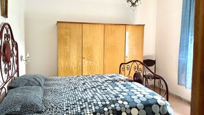 Un dormitorio con cama, armario, candelabro y ventana con cortinas.