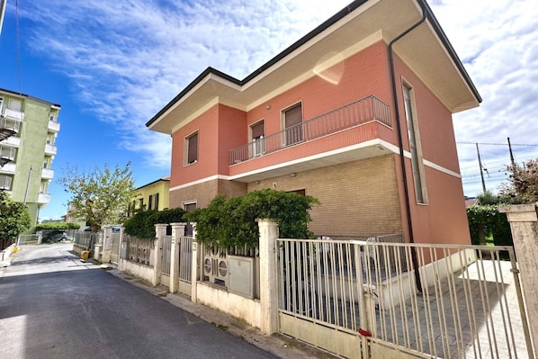 Un immeuble résidentiel à deux étages, doté d’un garage, d’une entrée sécurisée et d’un balcon à l’étage supérieur.
