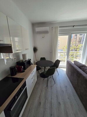 Moderni keittiö, jossa on ruokailutila, sohva ja näkymä ulos.