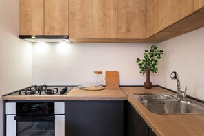 Eine Küche mit Holzausstattung, einem Edelstahlspülbecken, einem Herd und einem eingebauten Backofen.
