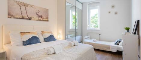 A bedroom with a bed, a bench, and a mirror.