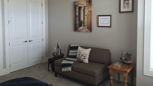 Una sala de estar con un sofá marrón, una mesita de madera, un cuadro enmarcado y una puerta.