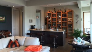 Una cocina moderna con una isla central, taburetes de bar y una zona de estar con sofá y sillones.