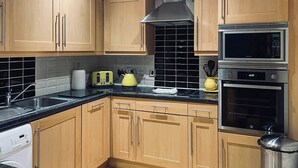 A modern kitchen with wooden cabinets, a stainless steel microwave, and an oven.
