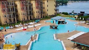 A hotel pool area with two water slides, a lifeguard tower, and a view of a body of water.