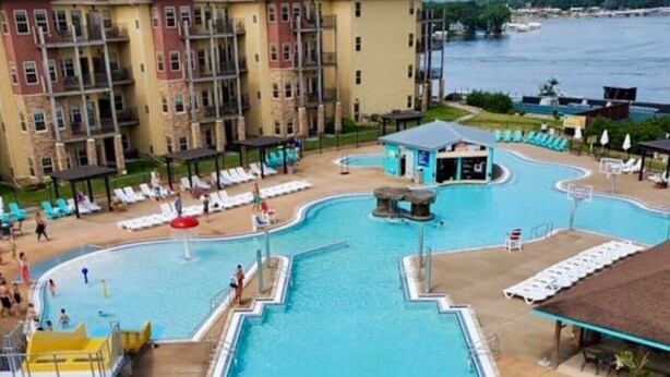 Zona de piscina de hotel con dos toboganes, una torre de socorrista y vista al agua.