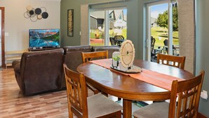 Un comedor con una mesa y sillas de madera, un televisor y vistas al exterior.