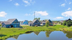 A residential area with houses, a pond, and a clear sky.