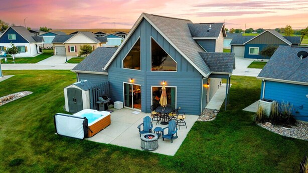 A residential house with a large deck, a hot tub, and outdoor furniture.