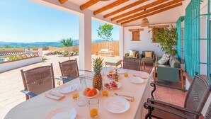 Un coin repas avec une table mise pour le petit-déjeuner, donnant sur une piscine et des montagnes.