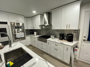 Una cocina moderna con armarios blancos, electrodomésticos de acero inoxidable y un horno empotrado.