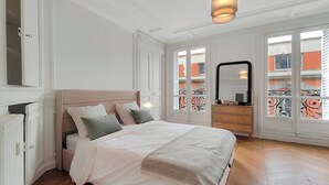 A bedroom with a bed, dresser, and large windows. - Amazing refurbished flat in Paris V (Paris)