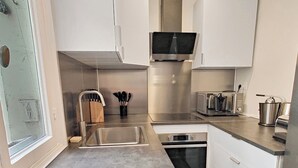 A modern kitchen with stainless steel appliances, a microwave, and a toaster. - Amazing refurbished flat in Paris V (Paris)