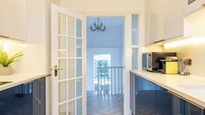 A modern kitchen with a central island, white cabinetry, and a chandelier. - Luxury Victorian Home London (London)