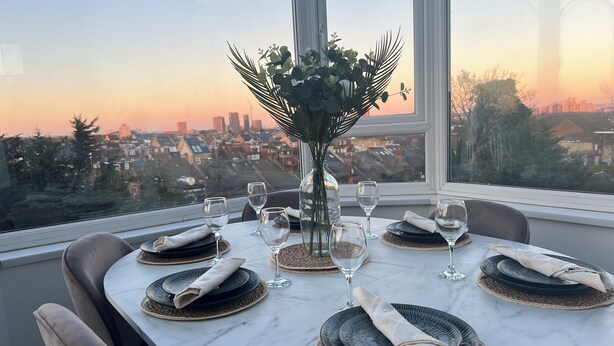 A dining table set for six with a city view at sunset. - Luxury Victorian Home London (London)