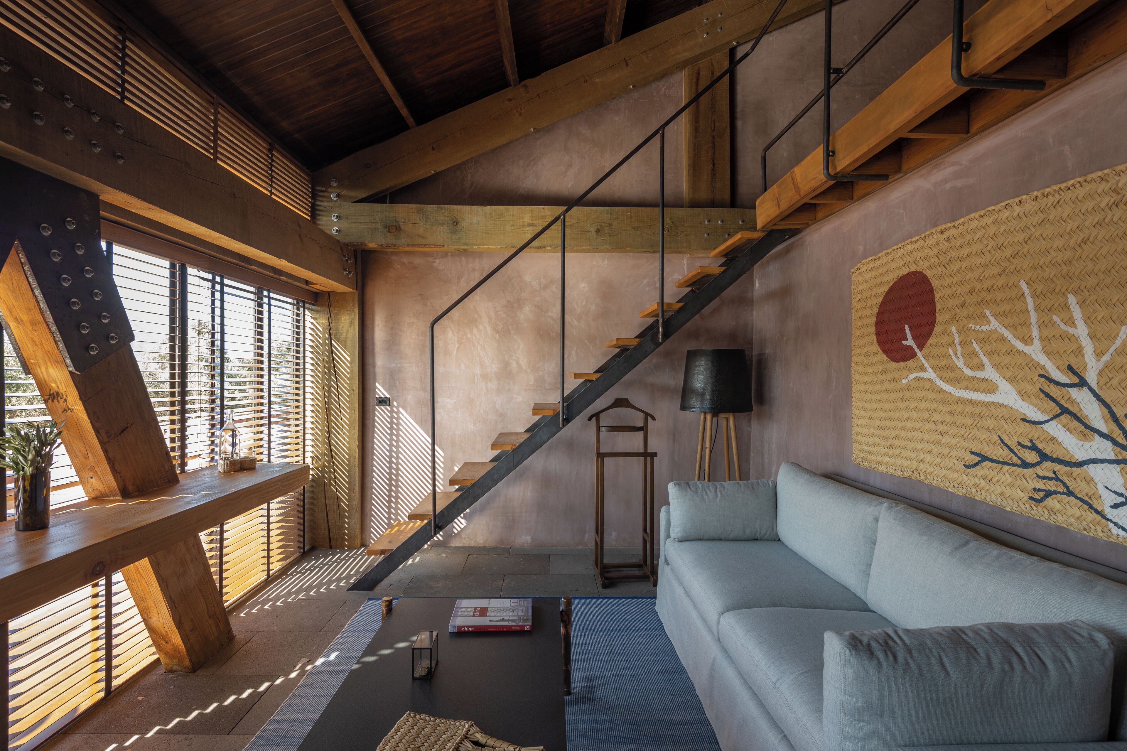 Un interior moderno con una escalera, un sofá y un gran mural en la pared.