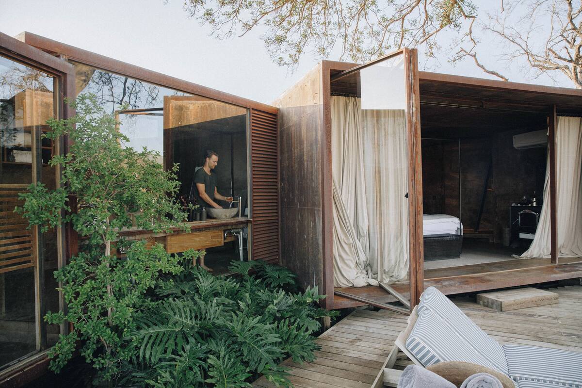 A modern, open-plan living space with a kitchen area, a sleeping area with a bed, and a wooden deck.