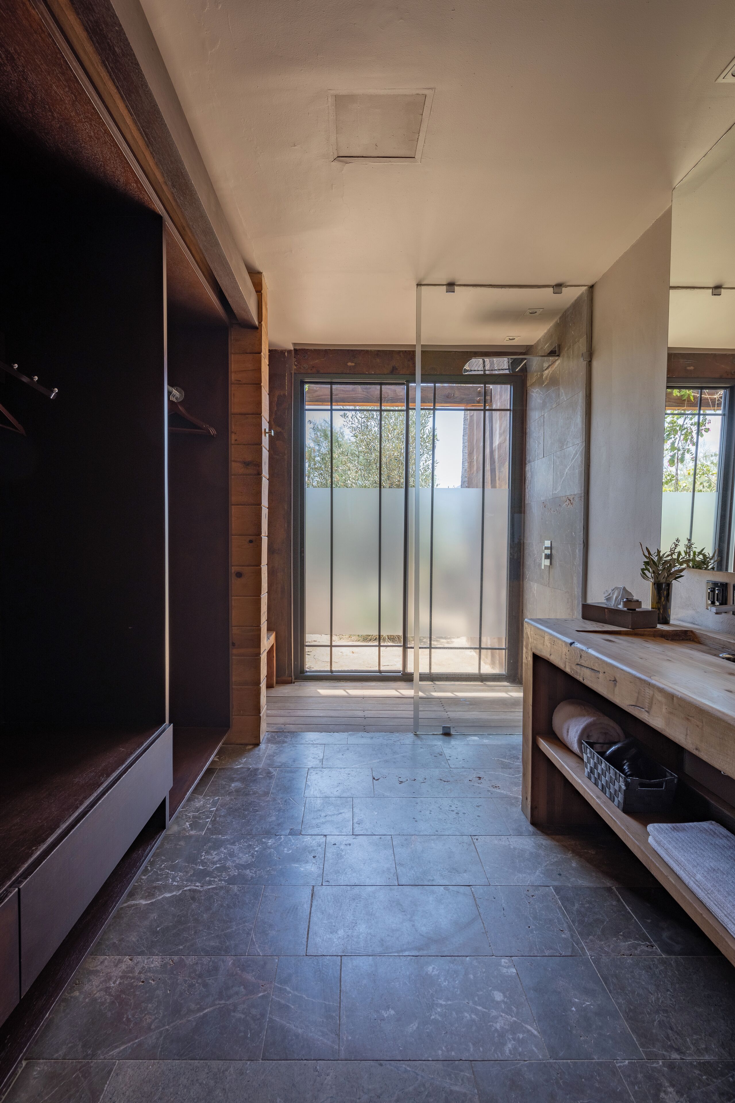 A modern bathroom with a large mirror, wooden cabinets, and a tiled floor.
