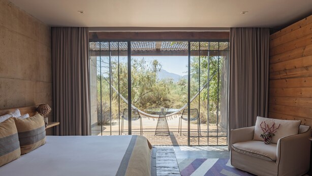 Un dormitorio con una cama grande, un sofá, una mesa de comedor con sillas y vistas al exterior.